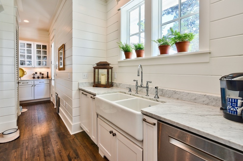 Inspiration for a beach style utility room in Miami with a farmhouse sink, shaker cabinets, white cabinets, white walls and dark hardwood floors.