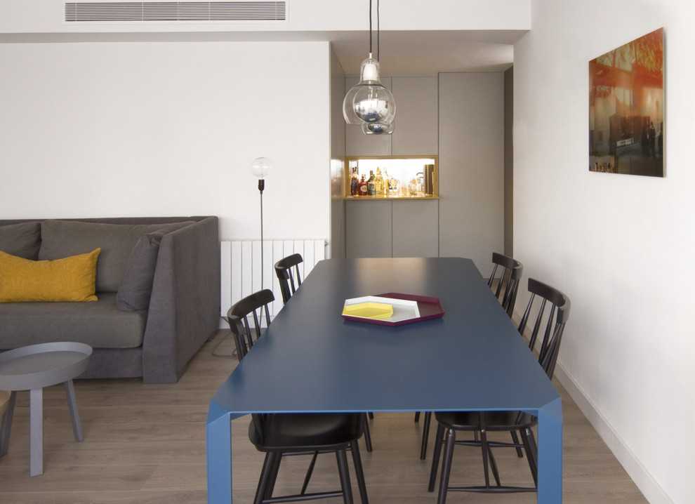 Modelo de comedor moderno con paredes blancas y suelo de madera en tonos medios