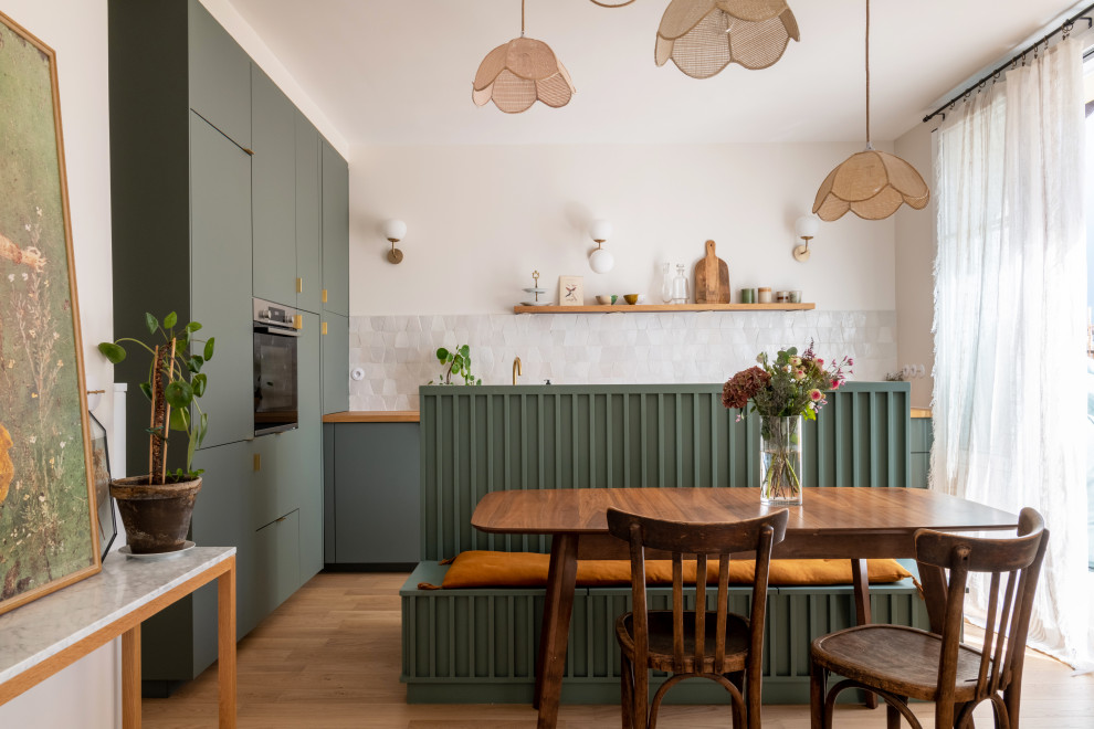 Inspiration for a mid-sized scandinavian l-shaped open plan kitchen in Paris with a drop-in sink, beaded inset cabinets, green cabinets, wood benchtops, beige splashback, limestone splashback, panelled appliances, light hardwood floors, with island, brown floor and brown benchtop.