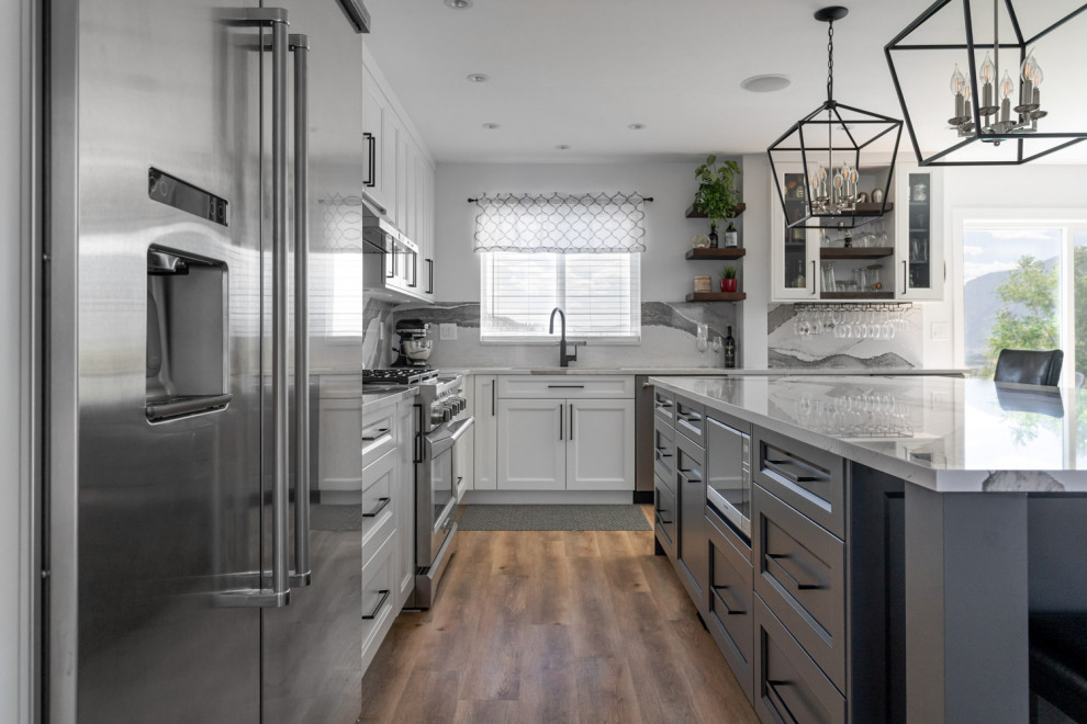 Inspiration for a mid-sized transitional u-shaped medium tone wood floor and brown floor eat-in kitchen remodel with an undermount sink, recessed-panel cabinets, white cabinets, quartz countertops, white backsplash, stone slab backsplash, stainless steel appliances, an island and white countertops