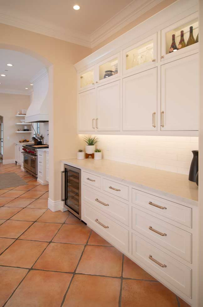 Inspiration for a large transitional kitchen pantry in San Francisco with an undermount sink, recessed-panel cabinets, white cabinets, quartz benchtops, white splashback, subway tile splashback, stainless steel appliances, terra-cotta floors, with island, multi-coloured floor and white benchtop.
