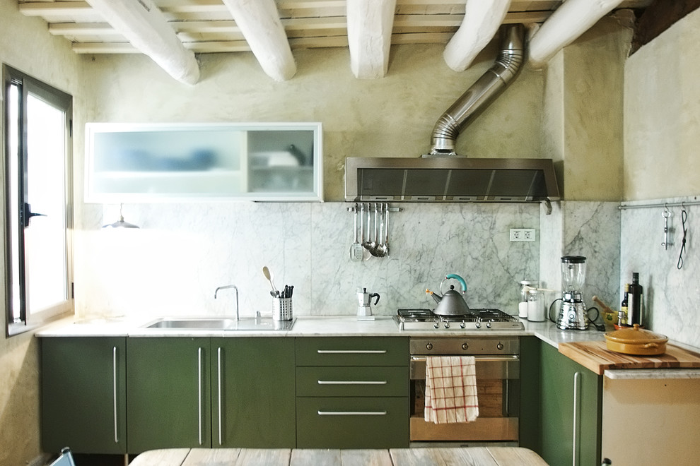 This is an example of a mid-sized contemporary l-shaped eat-in kitchen in Barcelona with a drop-in sink, flat-panel cabinets, green cabinets, marble benchtops, grey splashback, stone slab splashback, stainless steel appliances and no island.