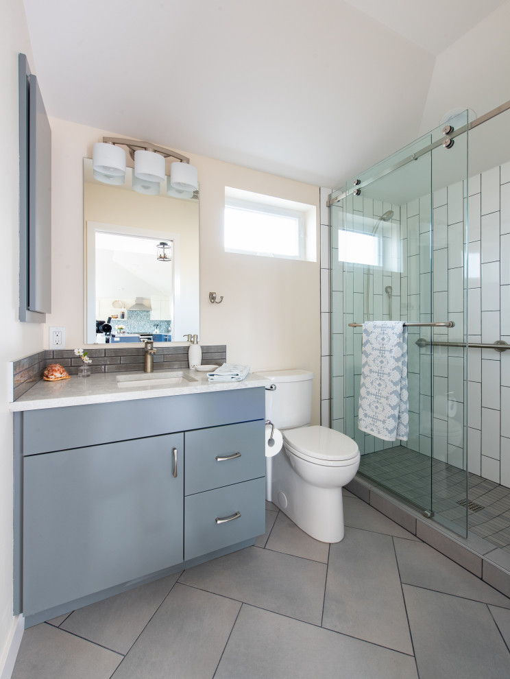Inspiration for a small nautical grey and cream ensuite bathroom in Seattle with flat-panel cabinets, grey cabinets, a two-piece toilet, white tiles, metro tiles, ceramic flooring, a submerged sink, grey floors, a sliding door, a single sink, a built in vanity unit and a vaulted ceiling.