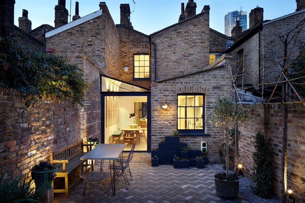 This is an example of a small transitional two-storey brick grey exterior in London with a gable roof.