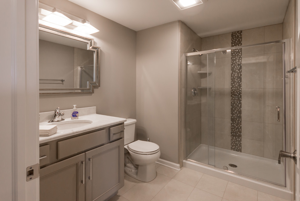 Mid-sized transitional kids bathroom in Milwaukee with shaker cabinets, beige cabinets, an alcove shower, a one-piece toilet, beige tile, porcelain tile, grey walls, porcelain floors, an undermount sink, engineered quartz benchtops, beige floor, a hinged shower door and white benchtops.