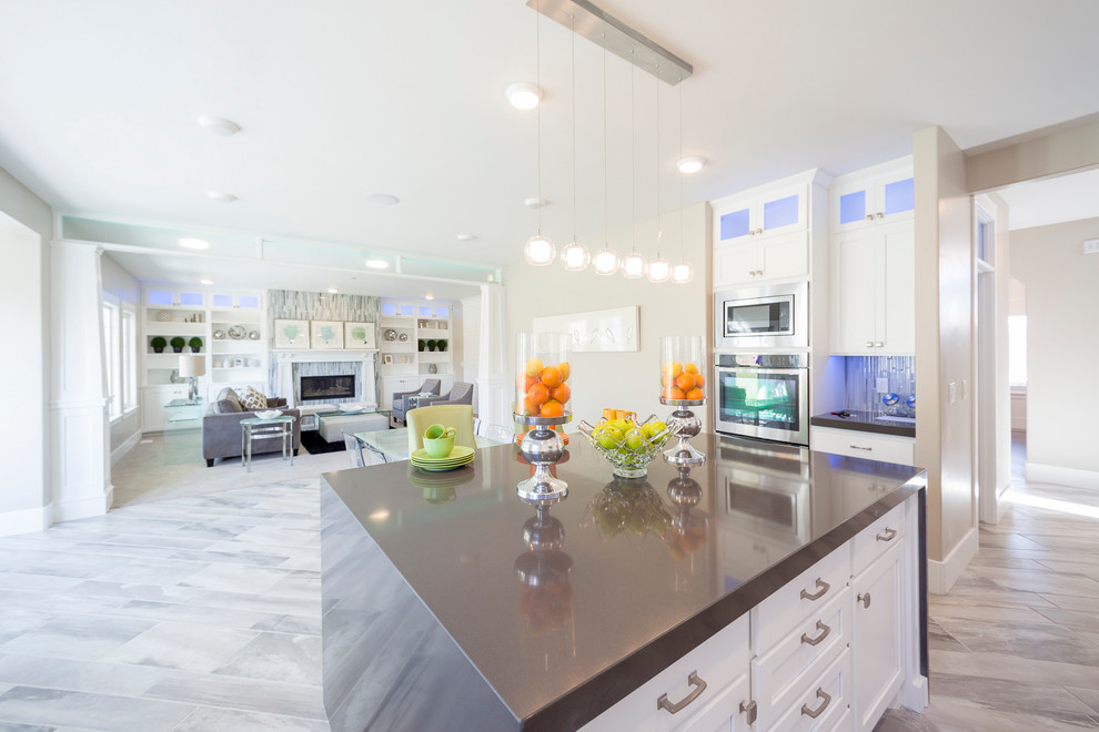 Inspiration for an expansive transitional l-shaped open plan kitchen in Salt Lake City with an undermount sink, shaker cabinets, white cabinets, solid surface benchtops, blue splashback, mosaic tile splashback, stainless steel appliances, porcelain floors and with island.