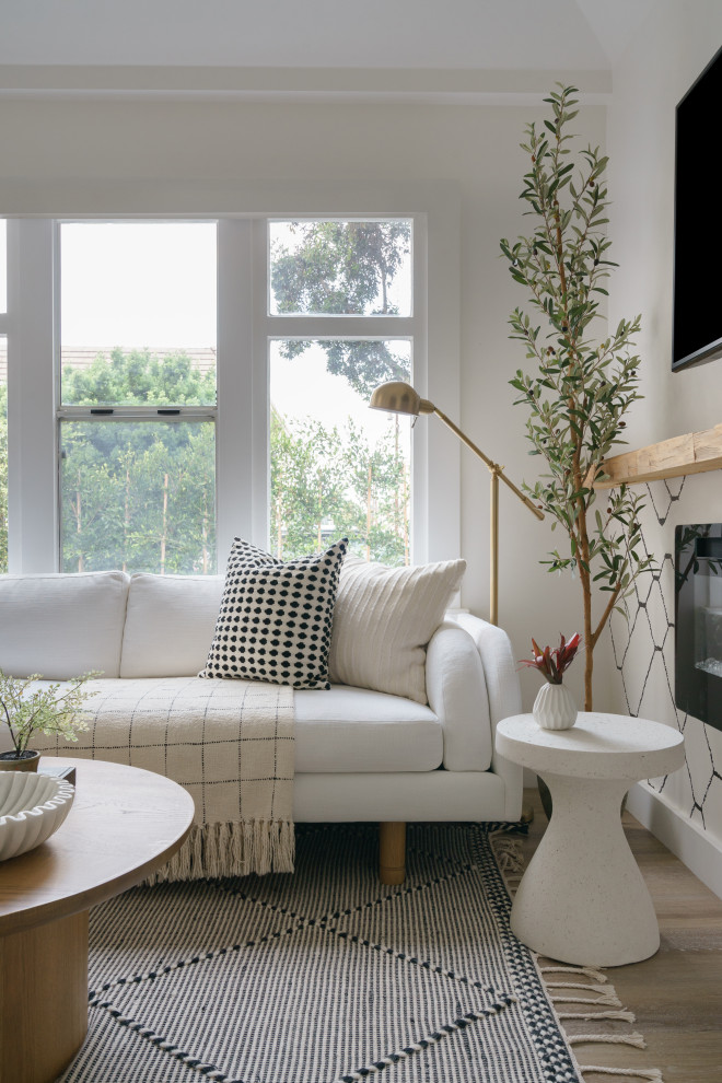 На фото: маленькая открытая гостиная комната в стиле фьюжн с белыми стенами, полом из ламината, подвесным камином, телевизором на стене, коричневым полом и сводчатым потолком для на участке и в саду с