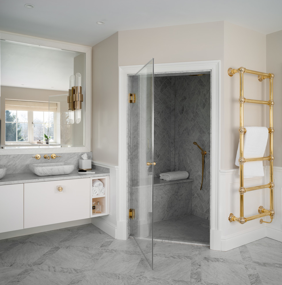 Design ideas for a mid-sized traditional kids wet room bathroom in London with shaker cabinets, blue cabinets, a freestanding tub, a one-piece toilet, gray tile, marble, grey walls, light hardwood floors, an integrated sink, limestone benchtops, grey floor, a hinged shower door and grey benchtops.