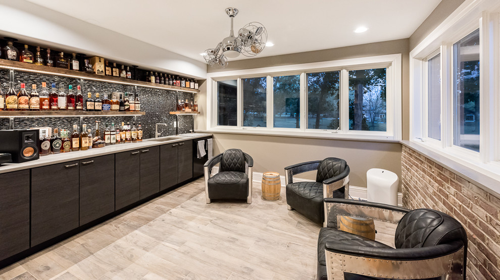 Photo of a mid-sized industrial single-wall wet bar in Chicago with an undermount sink, flat-panel cabinets, dark wood cabinets, metal splashback, light hardwood floors and beige floor.