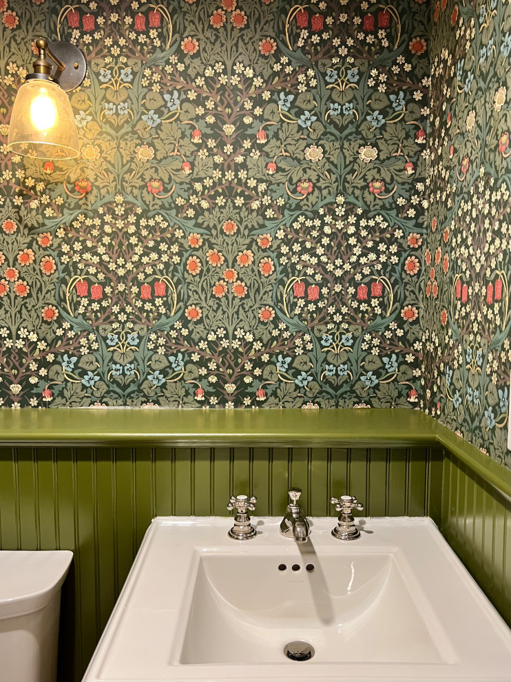 Cette image montre un petit WC et toilettes avec un mur vert et un plafond en papier peint.