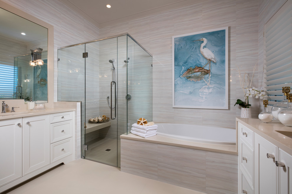Inspiration for a beach style master bathroom in Miami with recessed-panel cabinets, white cabinets, a drop-in tub, beige tile, beige walls, an undermount sink, beige floor, beige benchtops, a double shower and a hinged shower door.