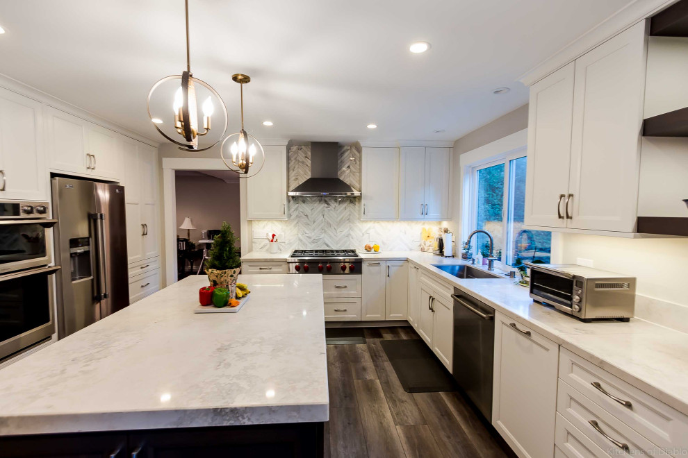 Open concept kitchen - large transitional u-shaped medium tone wood floor and gray floor open concept kitchen idea in San Francisco with an undermount sink, recessed-panel cabinets, white cabinets, quartz countertops, white backsplash, marble backsplash, stainless steel appliances, an island and white countertops