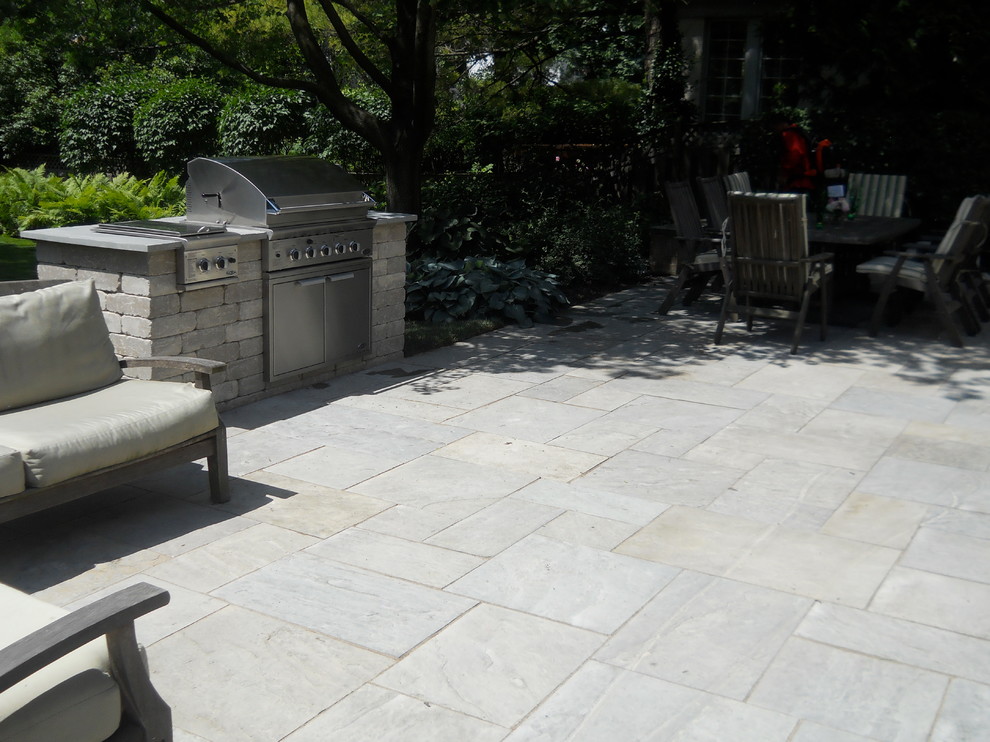This is an example of a mid-sized traditional backyard patio in Chicago with natural stone pavers.