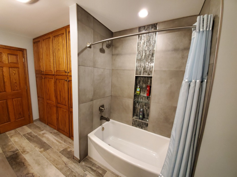 Mid-sized transitional master bathroom in Other with recessed-panel cabinets, dark wood cabinets, engineered quartz benchtops, blue benchtops, an alcove tub, gray tile, porcelain tile, blue walls, porcelain floors, an undermount sink, brown floor, a shower curtain, a niche and a double vanity.