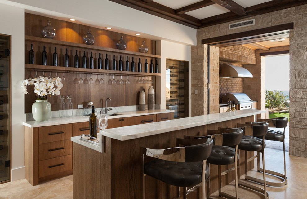 Design ideas for a mediterranean seated home bar in Orange County with an undermount sink, flat-panel cabinets, medium wood cabinets, brown splashback, timber splashback, beige floor and white benchtop.
