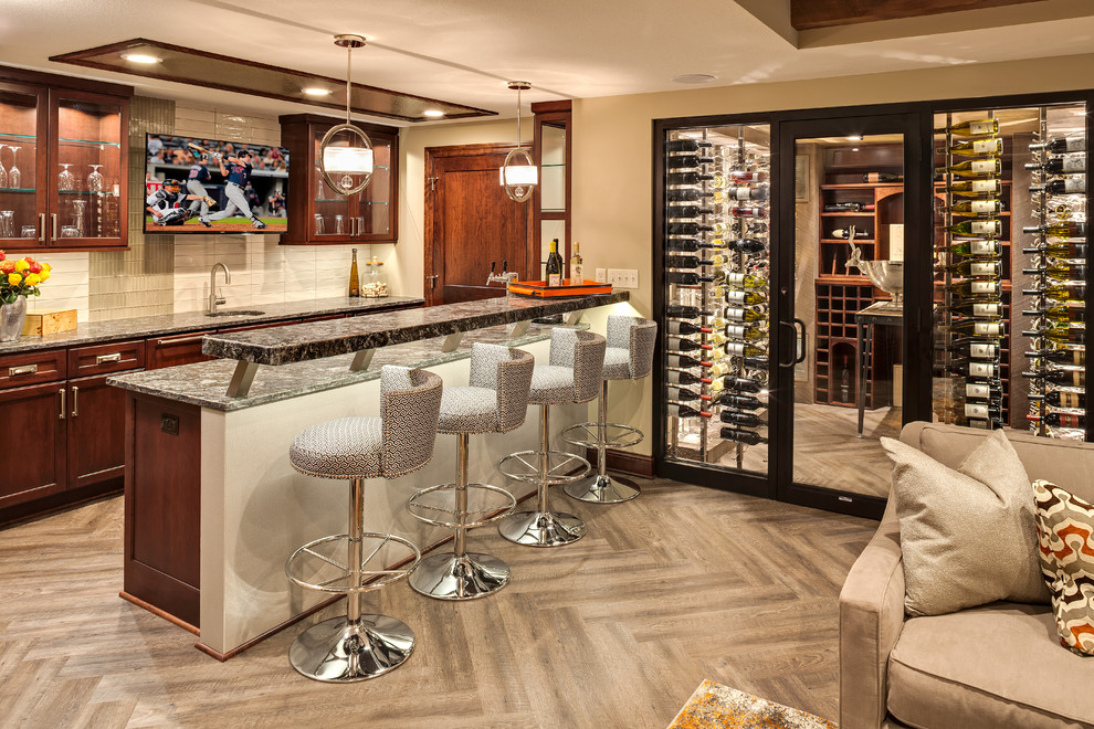 This is an example of a mid-sized contemporary galley seated home bar in Minneapolis with an undermount sink, recessed-panel cabinets, medium wood cabinets, granite benchtops, beige splashback, ceramic splashback and vinyl floors.