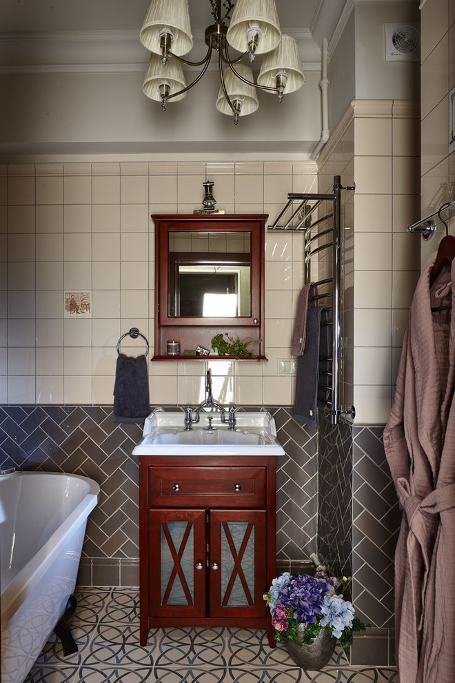 This is an example of a traditional bathroom in Moscow with a claw-foot tub, beige tile, gray tile, grey walls and a console sink.