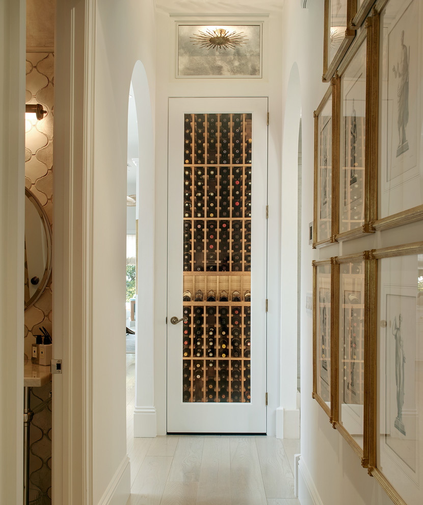 Design ideas for a mediterranean wine cellar in Miami with light hardwood floors, storage racks and beige floor.