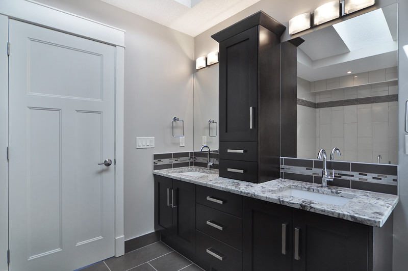 Large contemporary master bathroom in Calgary with shaker cabinets, dark wood cabinets, granite benchtops, a drop-in tub, beige tile, gray tile, porcelain tile, a corner shower, grey walls, porcelain floors, an undermount sink and a one-piece toilet.