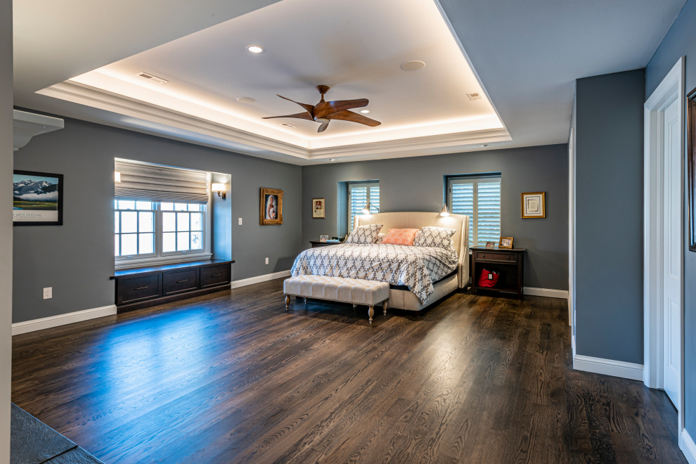 This is an example of a large traditional master bedroom in Denver with grey walls, dark hardwood floors, a standard fireplace, a wood fireplace surround and brown floor.