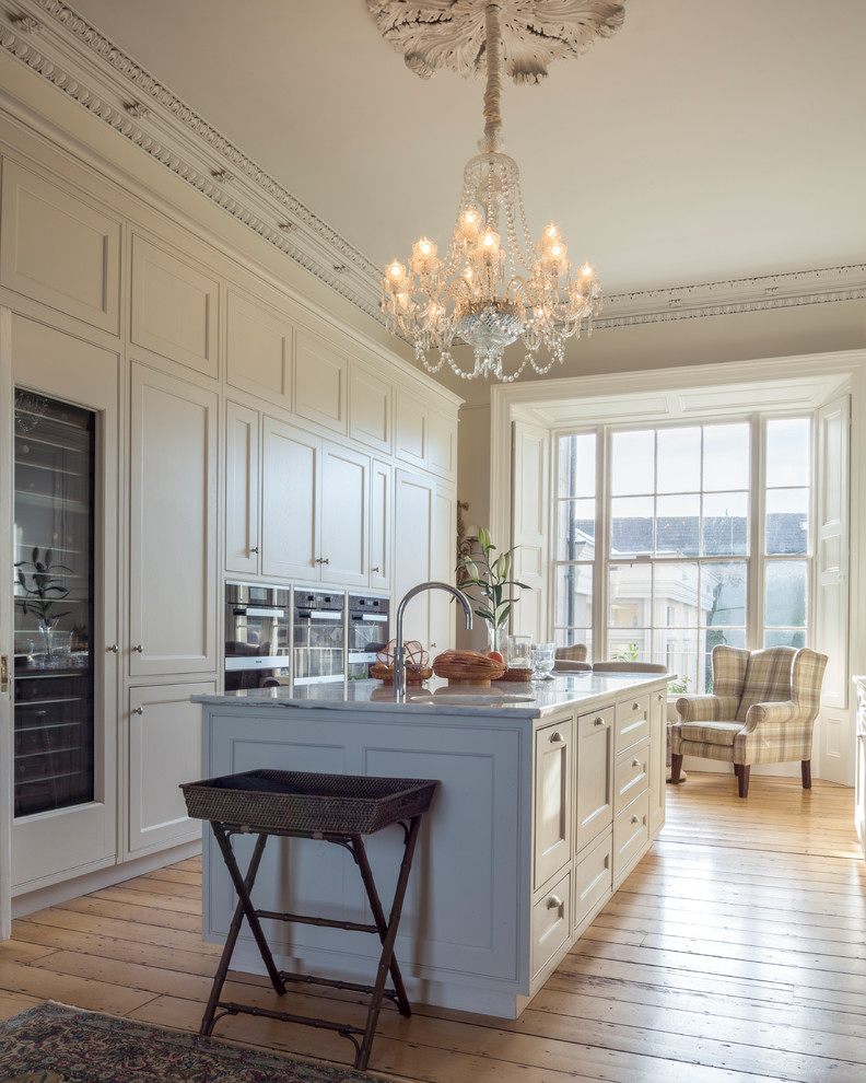Inspiration for a large traditional galley open plan kitchen in Dublin with shaker cabinets, beige cabinets, marble benchtops, black appliances and with island.