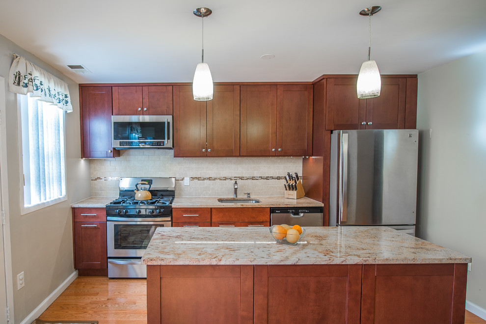 Mid-sized transitional single-wall eat-in kitchen in New York with an undermount sink, shaker cabinets, medium wood cabinets, granite benchtops, brown splashback, stainless steel appliances, medium hardwood floors, with island and stone tile splashback.