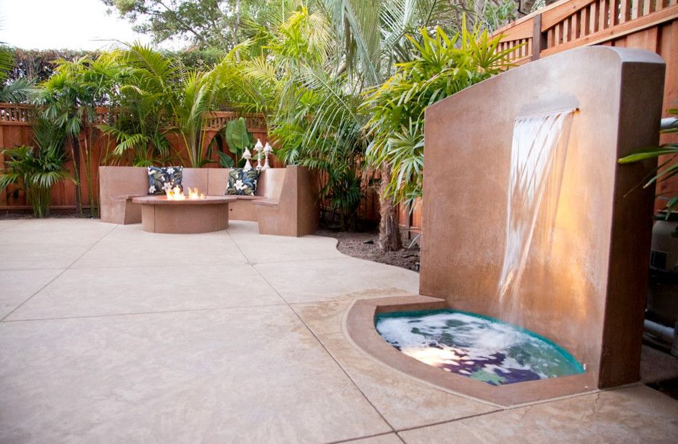 Design ideas for a mid-sized tropical backyard patio in San Francisco with a water feature, stamped concrete and no cover.