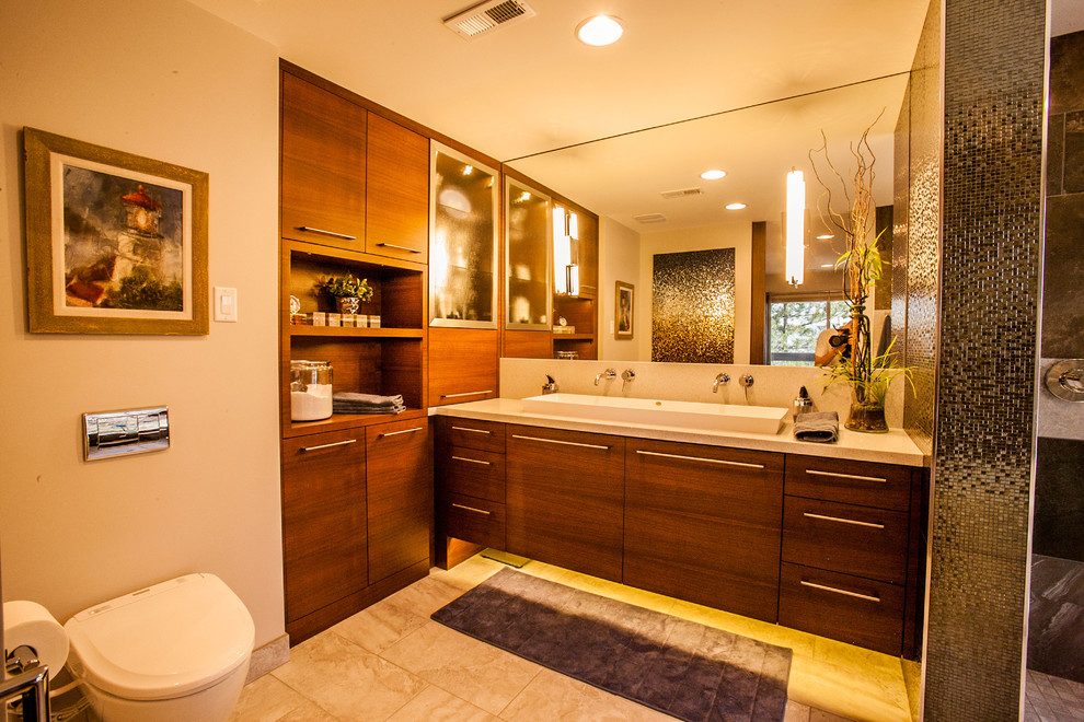 Large modern master bathroom in Salt Lake City with flat-panel cabinets, medium wood cabinets, an open shower, a bidet, gray tile, ceramic tile, beige walls, porcelain floors, a trough sink and granite benchtops.