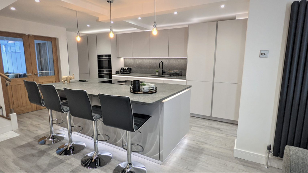 Design ideas for a large modern grey and white galley enclosed kitchen in Other with an integrated sink, white cabinets, quartz worktops, grey splashback, black appliances, an island, grey worktops and feature lighting.