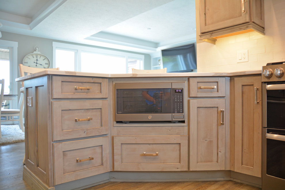 Inspiration for a small transitional u-shaped brown floor eat-in kitchen remodel with an undermount sink, recessed-panel cabinets, medium tone wood cabinets, quartz countertops, white backsplash, subway tile backsplash, stainless steel appliances, a peninsula and white countertops