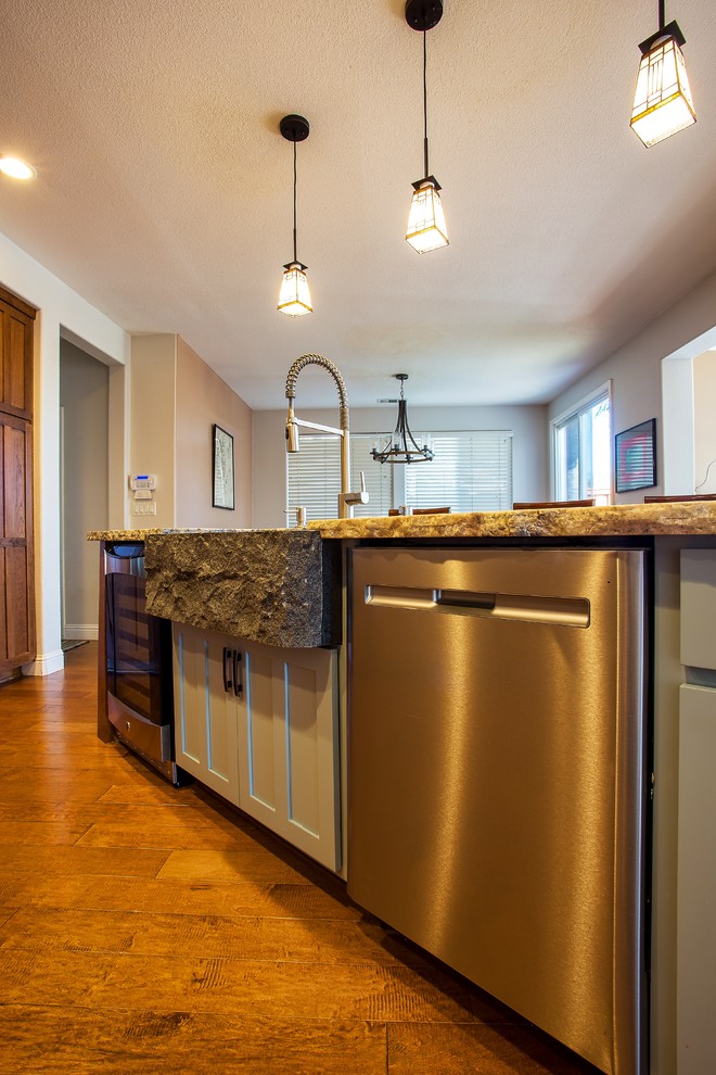 Example of a large mountain style dark wood floor and brown floor open concept kitchen design in Sacramento with a farmhouse sink, shaker cabinets, brown cabinets, granite countertops, beige backsplash, subway tile backsplash, stainless steel appliances, an island and brown countertops