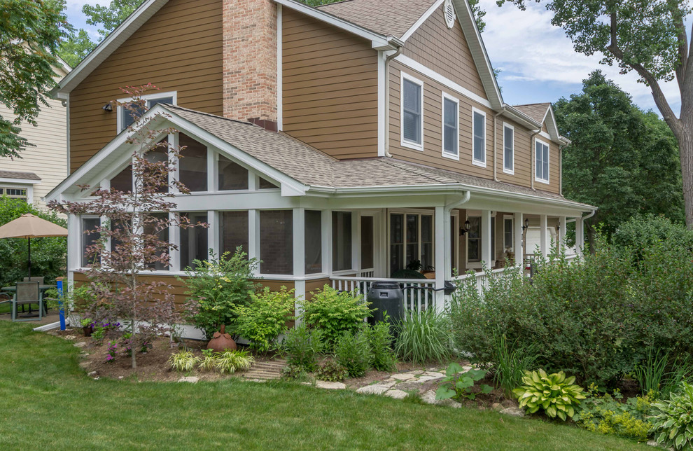This is an example of a mid-sized traditional side yard screened-in verandah in Chicago with concrete slab, a roof extension and glass railing.