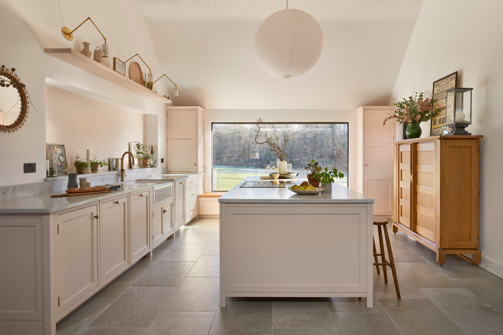 Inspiration for a large farmhouse grey and pink single-wall open plan kitchen in London with a belfast sink, shaker cabinets, pink cabinets, quartz worktops, pink splashback, black appliances, ceramic flooring, an island, multi-coloured floors, grey worktops and a vaulted ceiling.