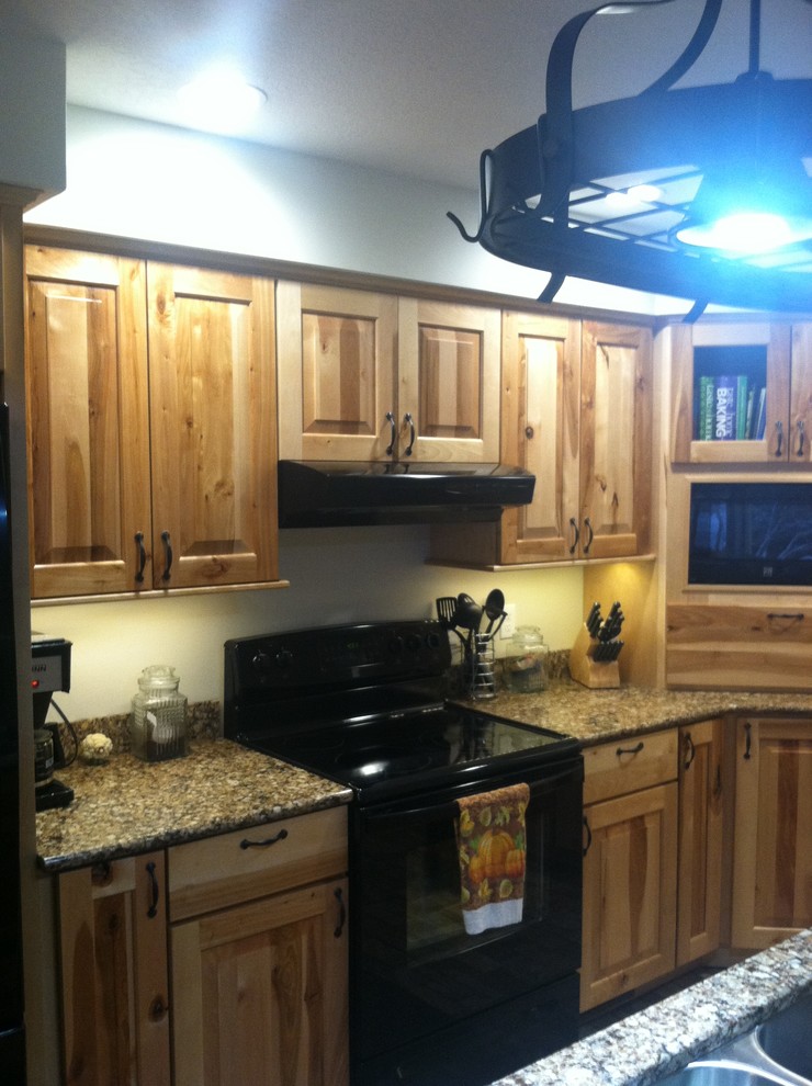 Inspiration for a mid-sized rustic l-shaped ceramic tile eat-in kitchen remodel with an undermount sink, raised-panel cabinets, light wood cabinets, quartz countertops, black appliances and an island