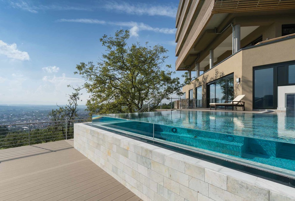 Design ideas for a mid-sized contemporary rooftop rectangular infinity pool in Stuttgart with natural stone pavers.
