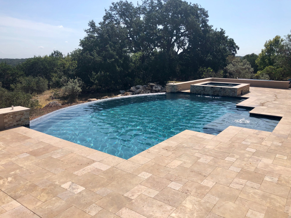 Inspiration for an expansive modern backyard custom-shaped infinity pool in Austin with with privacy feature and decking.
