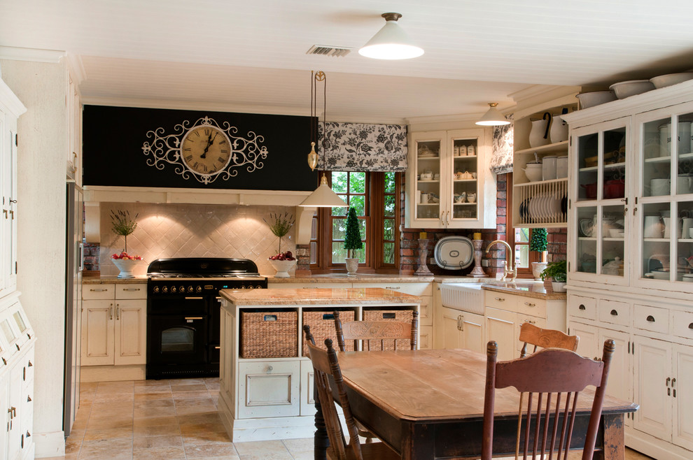This is an example of a mid-sized country u-shaped eat-in kitchen in Vancouver with a farmhouse sink, beige cabinets, beige splashback, black appliances and with island.