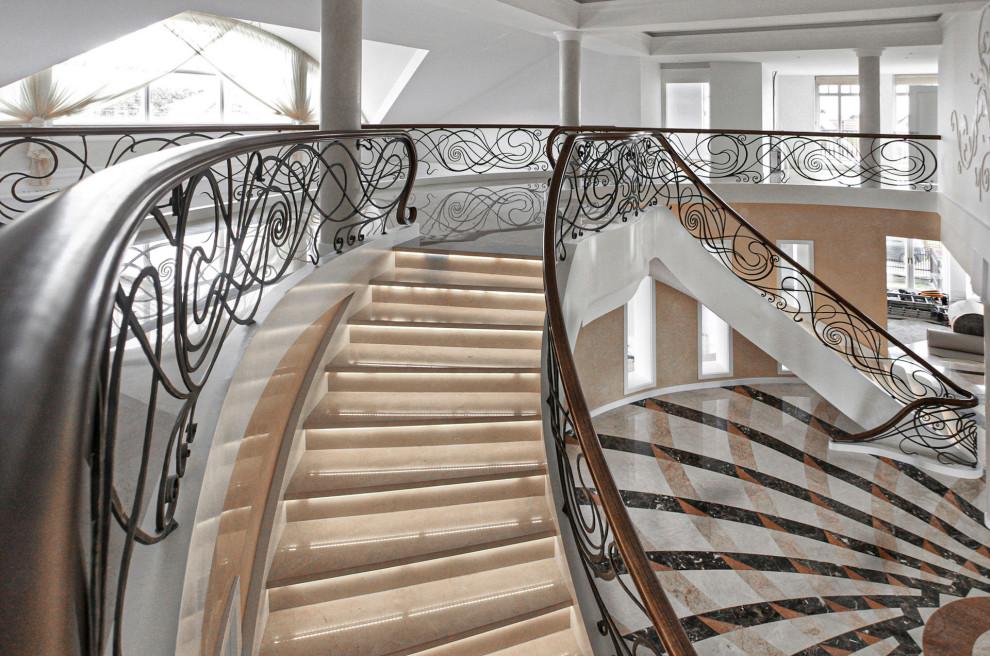 На фото: изогнутая лестница в классическом стиле с ступенями из известняка, подступенками из известняка и металлическими перилами