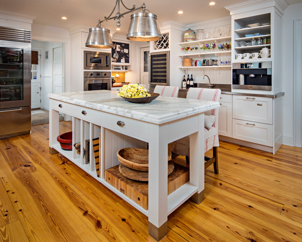 Example of a mid-sized transitional l-shaped medium tone wood floor eat-in kitchen design with white cabinets, marble countertops, stainless steel appliances, an island, shaker cabinets, white backsplash and wood backsplash