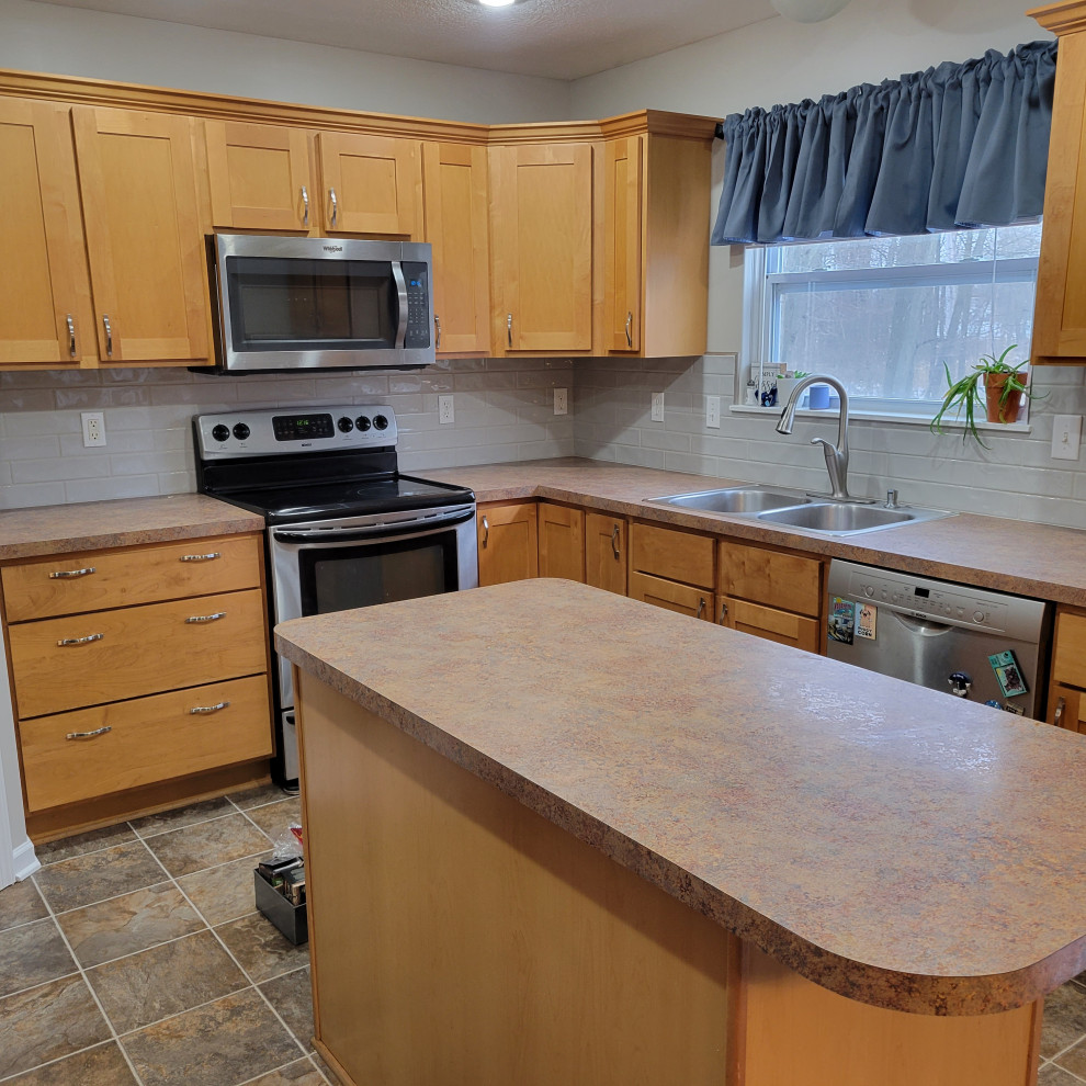 Eat-in kitchen - mid-sized l-shaped vinyl floor and multicolored floor eat-in kitchen idea with a double-bowl sink, flat-panel cabinets, light wood cabinets, laminate countertops, gray backsplash, ceramic backsplash, stainless steel appliances, an island and multicolored countertops