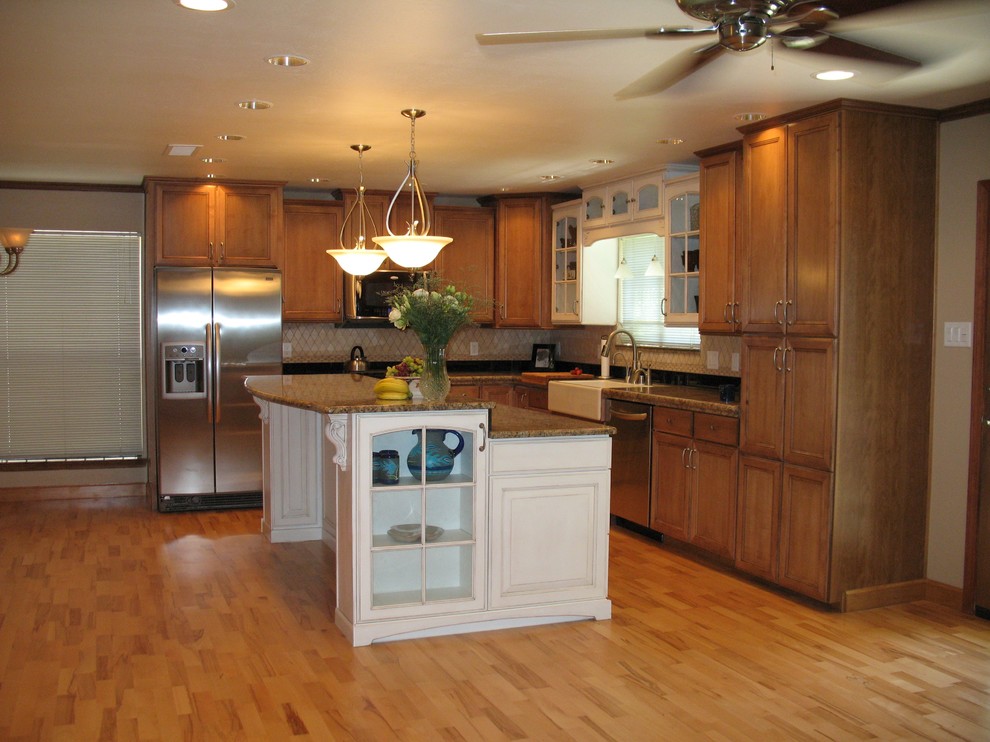 Mid-sized l-shaped light wood floor eat-in kitchen photo in Albuquerque with a farmhouse sink, raised-panel cabinets, granite countertops, beige backsplash, stone tile backsplash, stainless steel appliances, an island and white cabinets