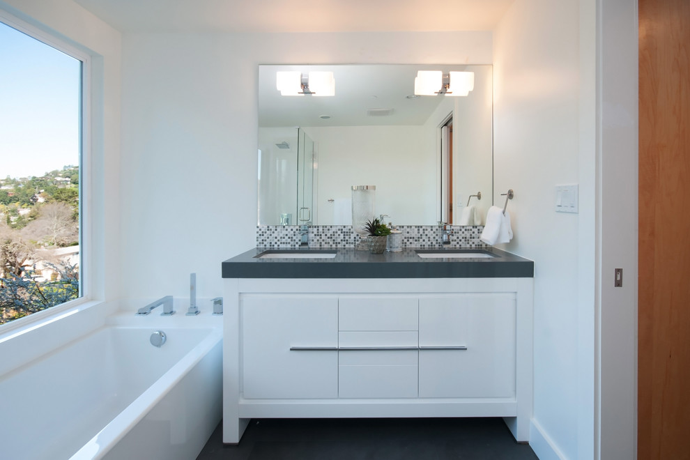 This is an example of a large midcentury master bathroom in San Francisco with flat-panel cabinets, white cabinets, a drop-in tub, a corner shower, a one-piece toilet, white tile, porcelain tile, white walls, dark hardwood floors, an undermount sink, engineered quartz benchtops, brown floor, a hinged shower door and grey benchtops.