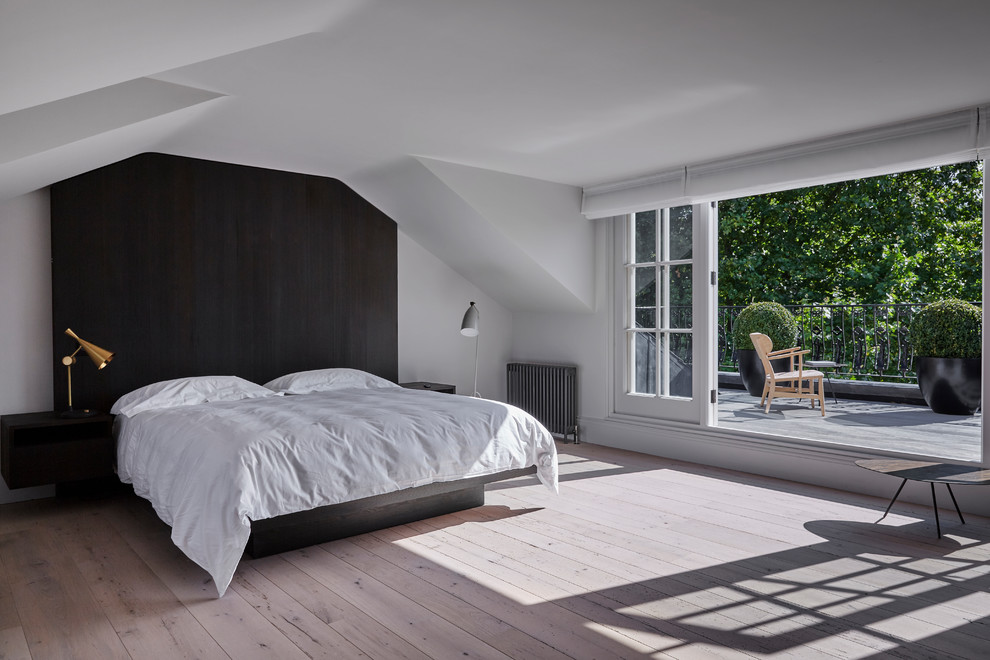 Inspiration for a mid-sized contemporary bedroom in London with white walls, light hardwood floors and no fireplace.