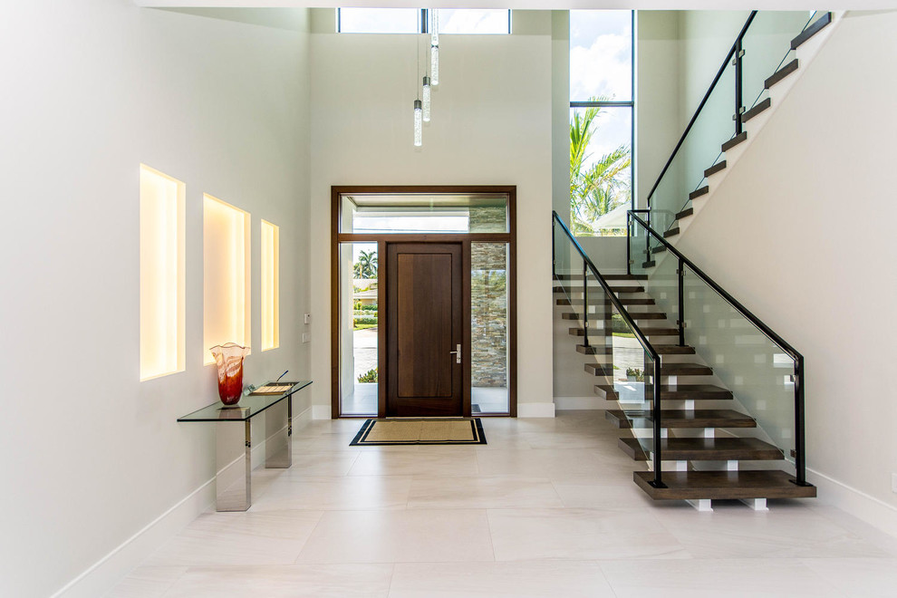 This is an example of a mid-sized contemporary foyer in Miami with grey walls, porcelain floors, a single front door and a dark wood front door.