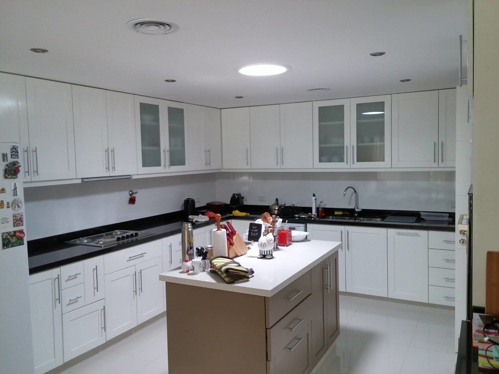 Large minimalist l-shaped eat-in kitchen photo with white cabinets, granite countertops and white backsplash