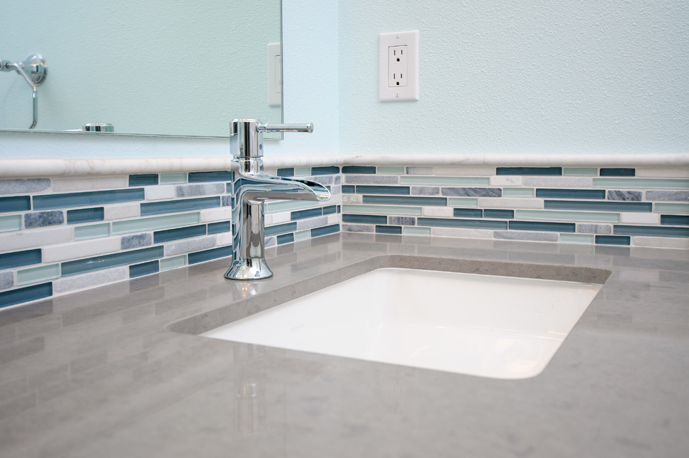 This is an example of a contemporary bathroom in San Francisco with an undermount sink, white cabinets, solid surface benchtops, an open shower, a two-piece toilet, white tile, porcelain tile, blue walls and porcelain floors.