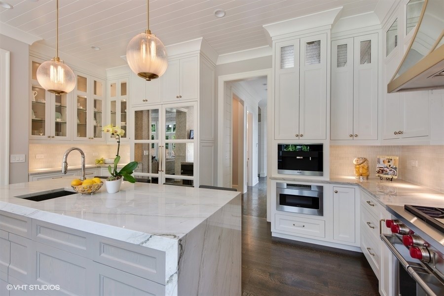 Large transitional u-shaped medium tone wood floor and brown floor eat-in kitchen photo in Chicago with a drop-in sink, recessed-panel cabinets, white cabinets, quartzite countertops, gray backsplash, porcelain backsplash, paneled appliances, an island and gray countertops