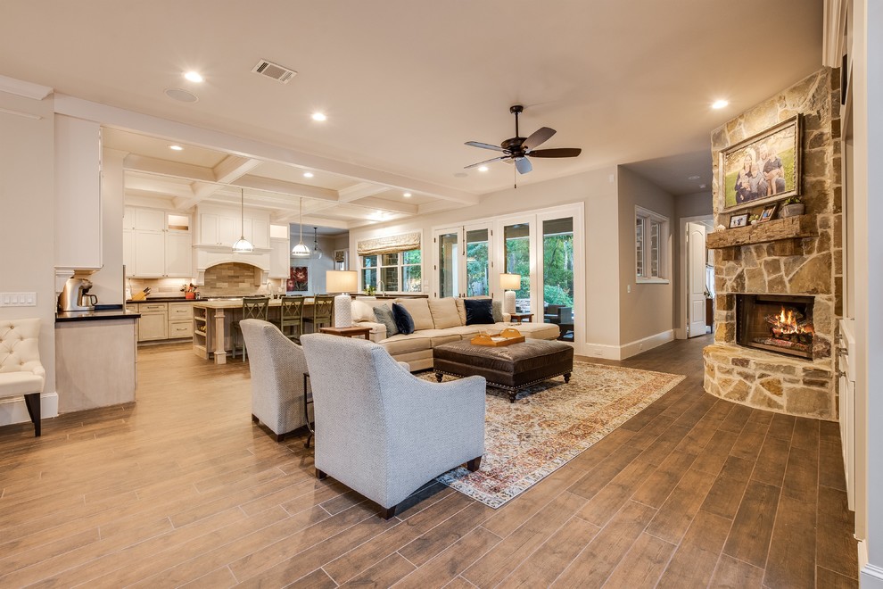 Large transitional open concept family room with white walls, a standard fireplace, a stone fireplace surround, a built-in media wall, brown floor and porcelain floors.