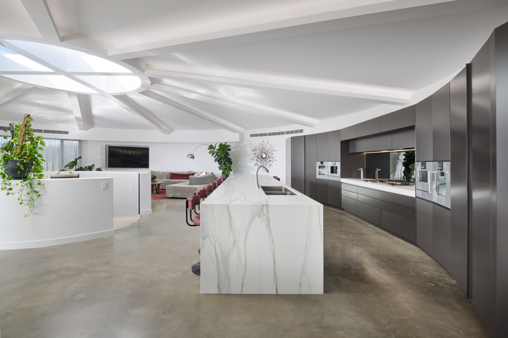 Expansive contemporary galley kitchen in Perth with a double-bowl sink, flat-panel cabinets, tile benchtops, concrete floors, with island, grey floor, grey cabinets, stainless steel appliances, white benchtop and exposed beam.