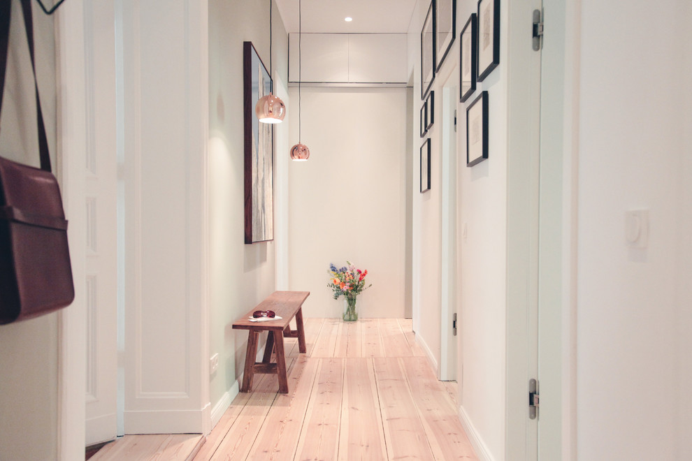 This is an example of a large contemporary hallway in Berlin with white walls and light hardwood floors.